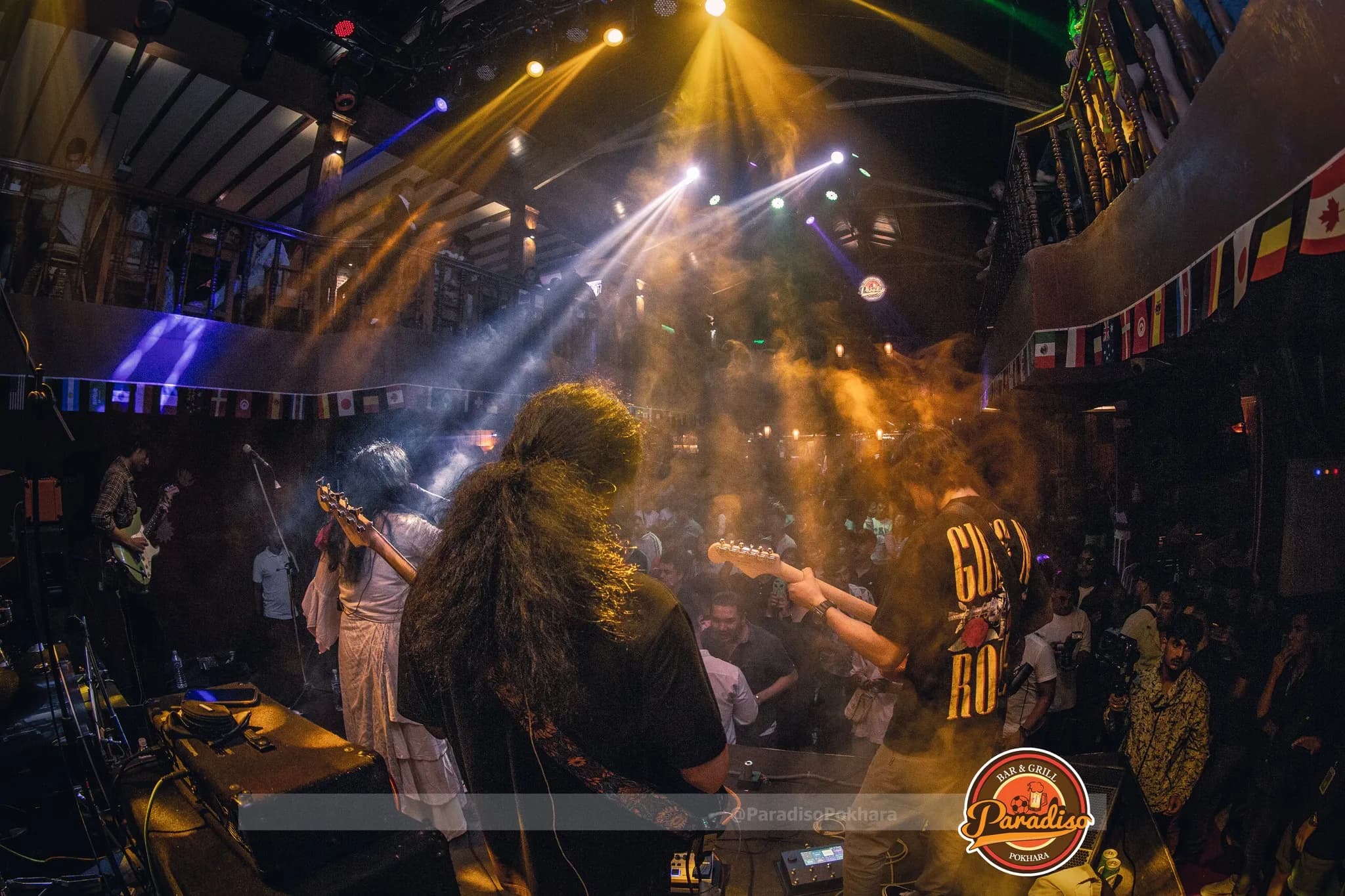 The view from behind the band, lights cutting through haze over the floor
